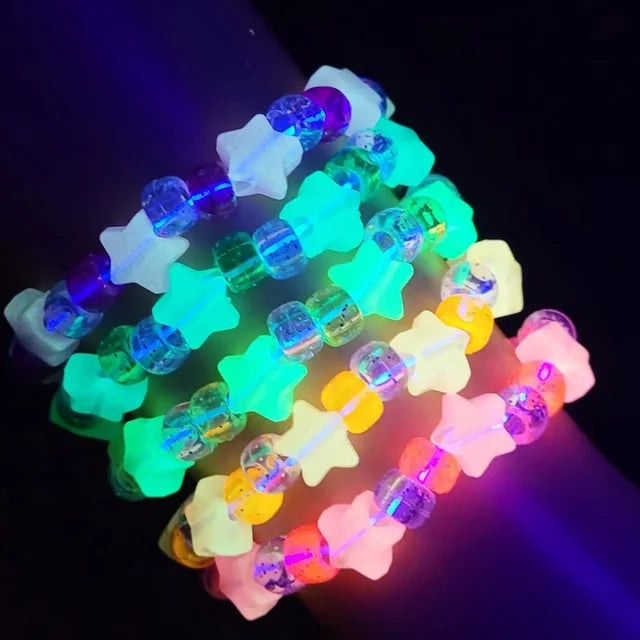 Stacked kandi rave bracelets of UV-glow star beads and pony beads in neon colors on a wrist