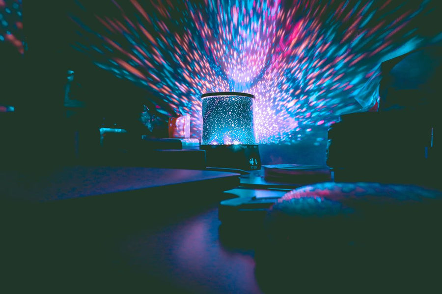 Galaxy star projector casting pink and blue stars across a dark room