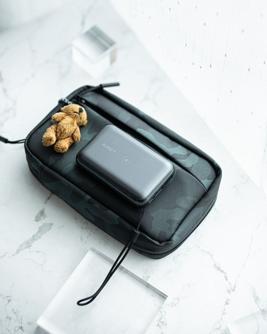 Crossbody sling pouch with a power bank resting on top, tech flatlay