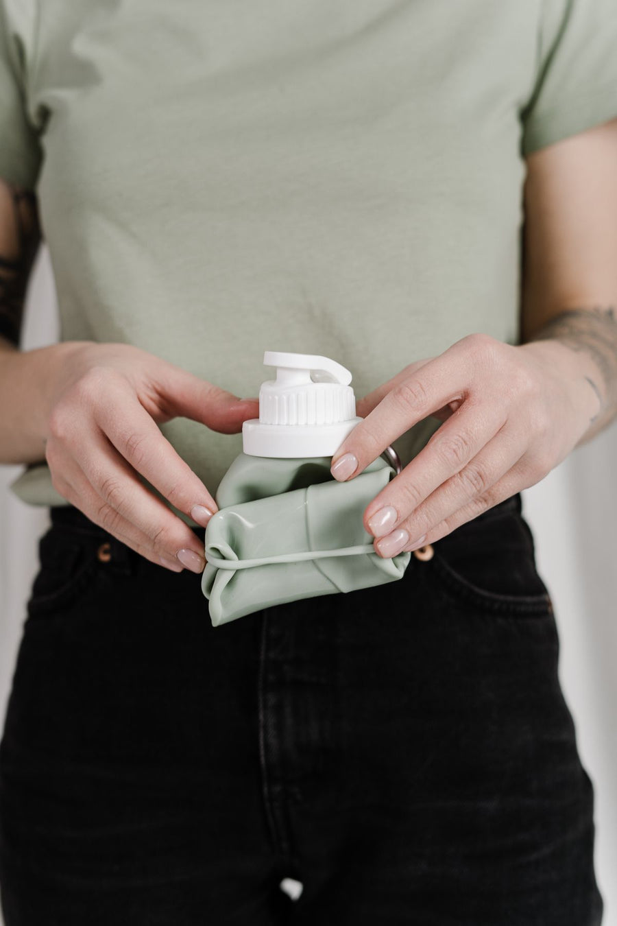 Hands holding a rolled-up collapsible silicone water bottle with flip cap