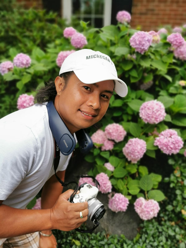 Person outdoors wearing a bladeless rechargeable neck fan around the neck