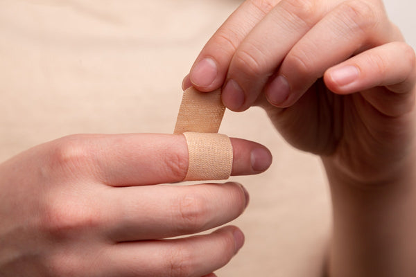 Adhesive bandage plaster being applied to a finger, first aid wound care