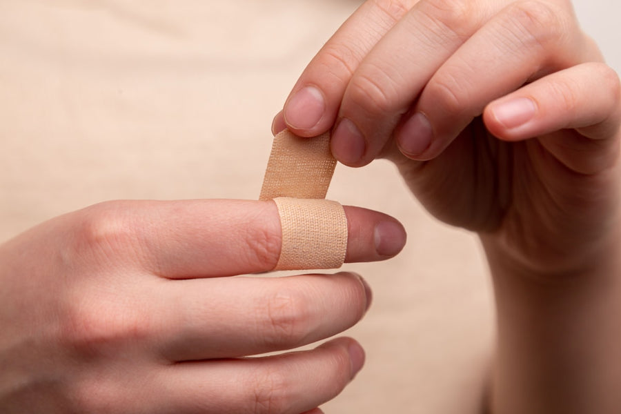 Adhesive bandage plaster being applied to a finger, first aid wound care