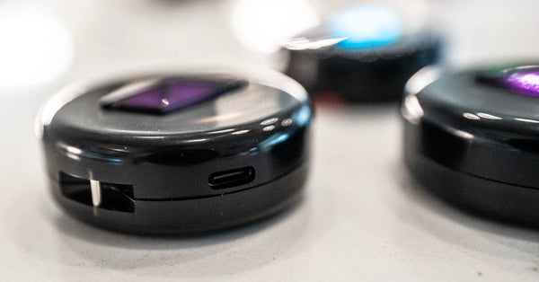 Modern offline friend-finder compass gadget, small puck-shaped device with glowing display and USB-C